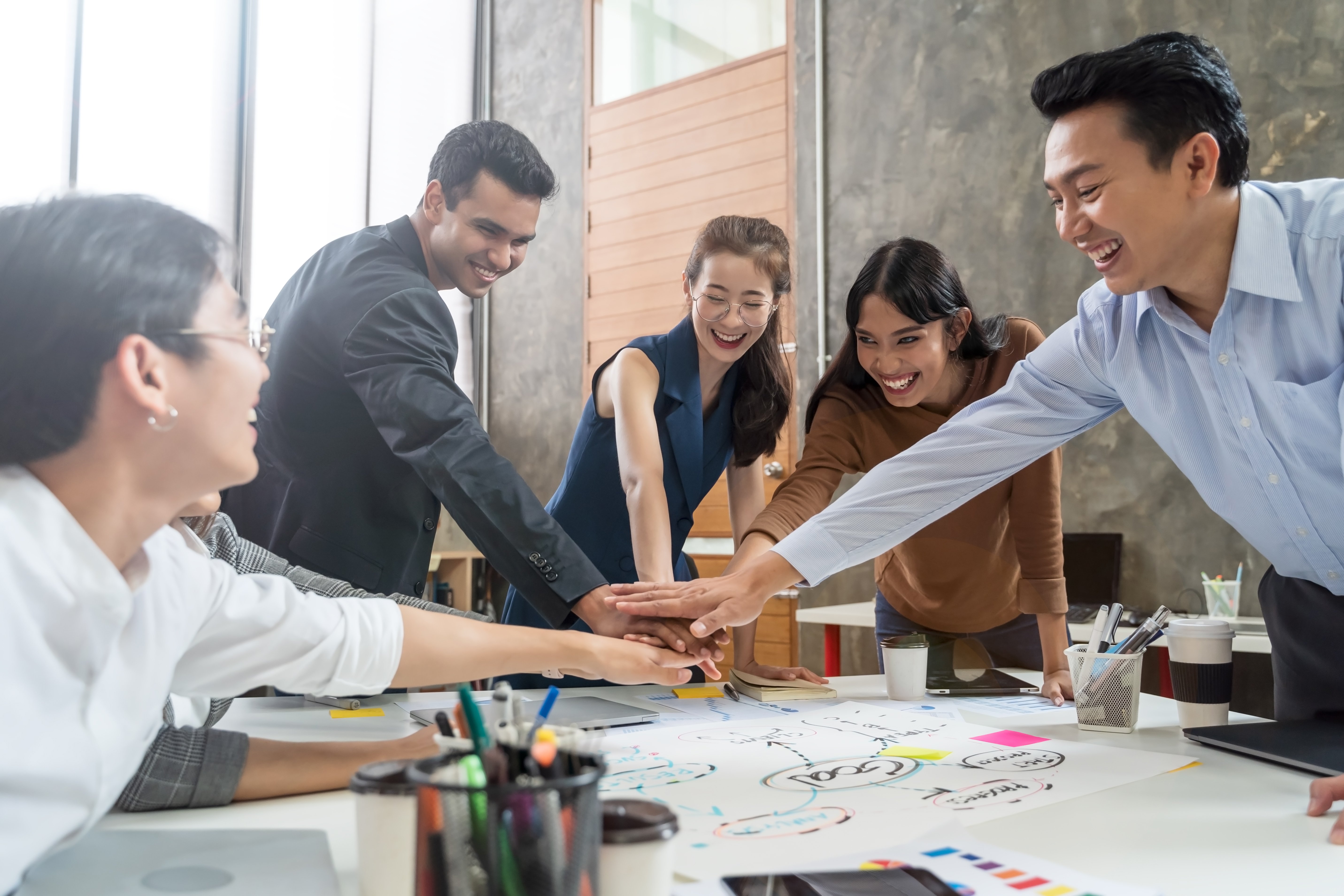 smiling-colleagues-stacking-hands-office
